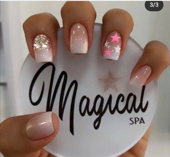 103 Nails with short square stars with nude enamel with white and pink stars on the ring finger, glitter and rhinestones on the index finger